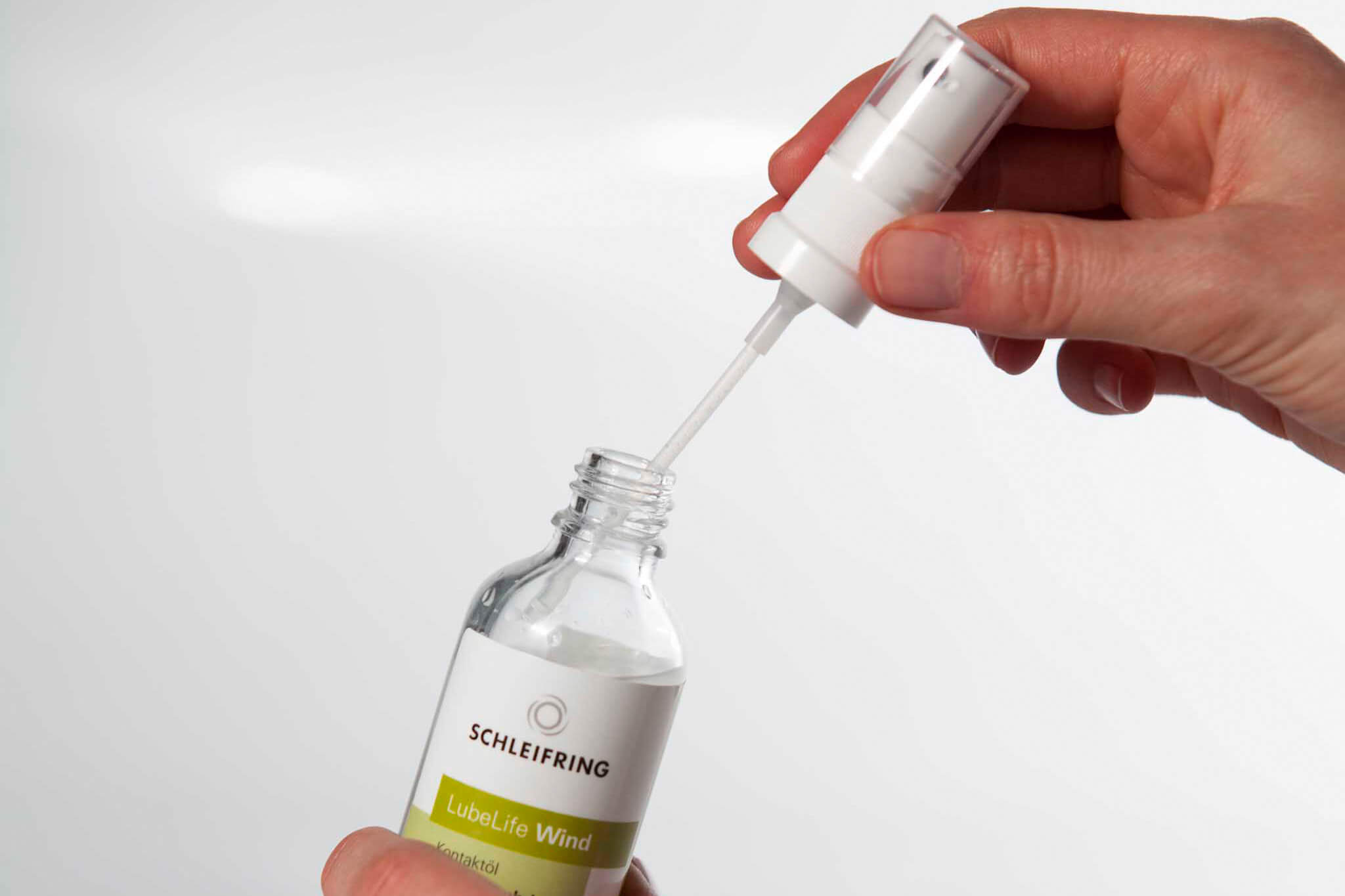Hand entnimmt mit Pipette Kontaktöl aus einer Flasche LubeLife Wind von SCHLEIFRING.